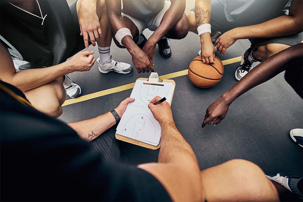 Photo présentant un coach de basket expliquant une stratégie à ses athlètes.