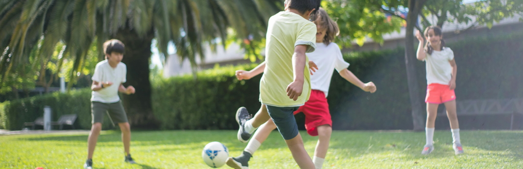 Groupe d'enfant jouant au football dans un parc.